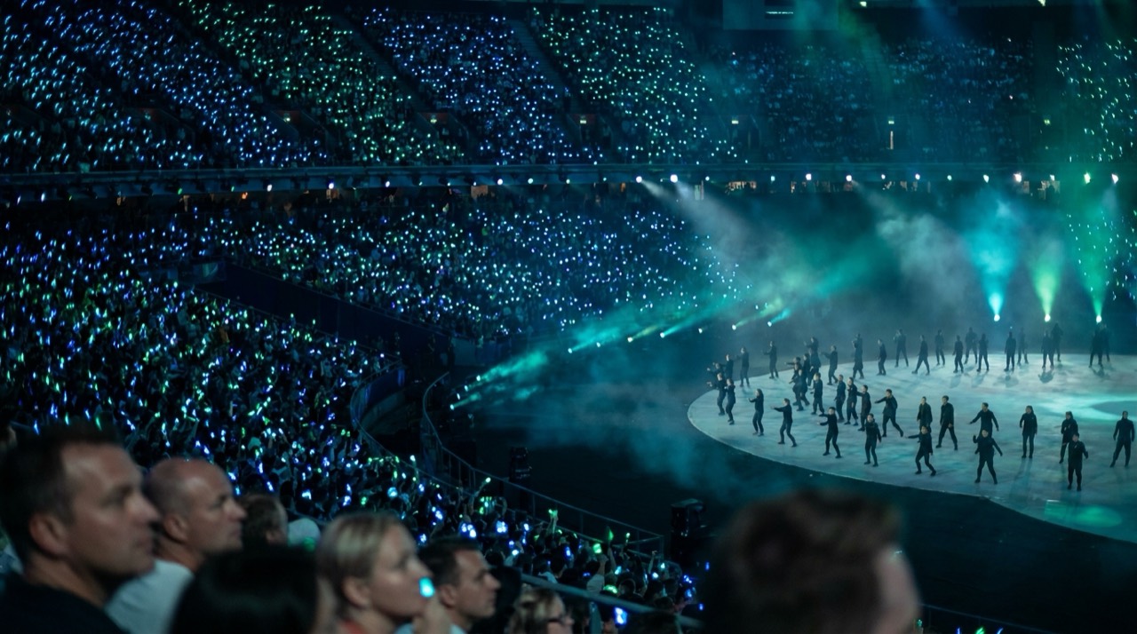 Photo : stade olympique en cérémonie, foule immense et jeux de lumière, grand spectacle, bleu-vert